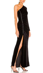 Robe longue noire à une épaule fendue sur fond de velours à motif diamant.