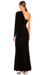 Robe longue noire à une épaule fendue sur fond de velours à motif diamant.